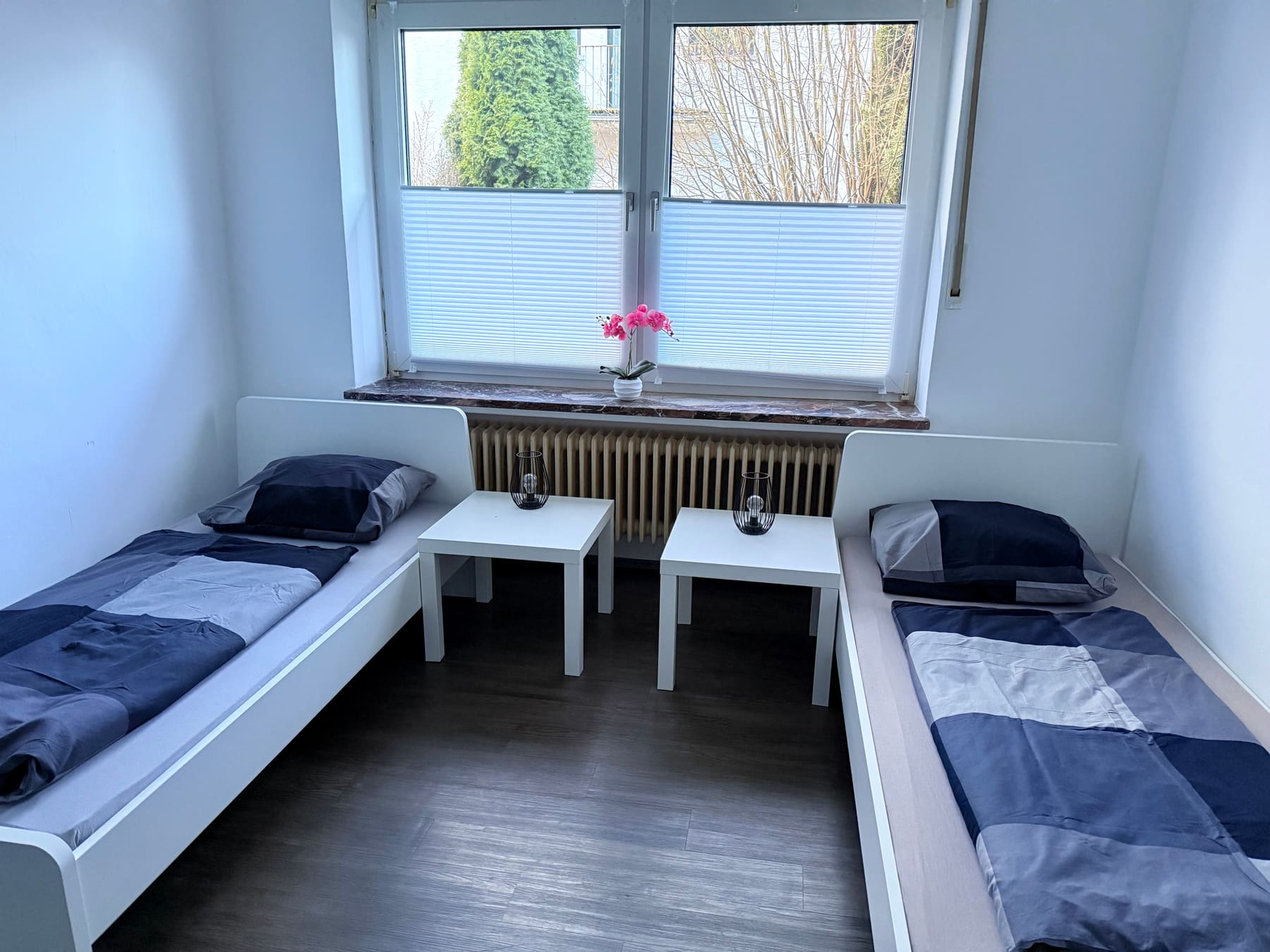 Schlafzimmer mit zwei Einzelbetten und Nachttischen am Fenster